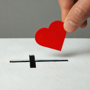 Donation of your heart as symbol of love for the religion of Chr Donation of your heart as symbol of love for the religion of Christianity. Box for donations with slot in the form of Christian christe. Man puts hand donations.